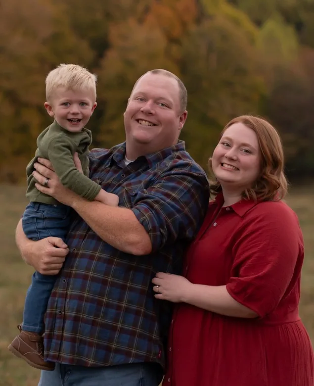 Mason Gunter, surveying manager at Doss Land Surveying, outdoors in autumn with his wife and young son.