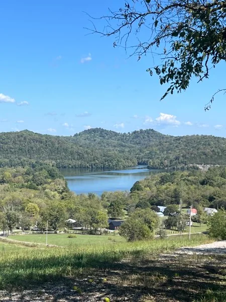 View from a wooded ridge over a broad Middle Tennessee valley, with a lake, farmland and a small town spread out below.
